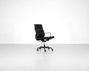 Peut inclure: Chaise de bureau en cuir noir avec dossier haut et accoudoirs. La chaise a une base à cinq roues et une fonction pivotante. La chaise est conçue pour le confort et le soutien, adaptée à un cadre domestique ou de bureau.