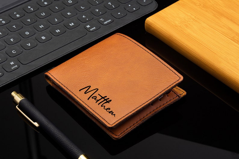 Puede incluir: Una cartera de cuero marr&oacute;n con el nombre "Matthew" grabado en la parte delantera.