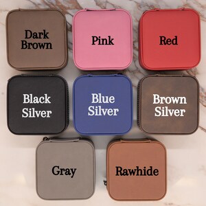 Puede incluir: Nueve cajas de joyer&iacute;a cuadradas en diferentes colores, incluyendo marr&oacute;n oscuro, rosa, rojo, negro, azul, marr&oacute;n, gris y cuero crudo. Cada caja tiene un color diferente y una etiqueta con el nombre del color.
