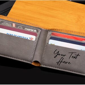 May include: A gray leather wallet with multiple card slots. The wallet is open and has several credit cards inside. The text "Your Text Here" is embossed on the inside of the wallet.