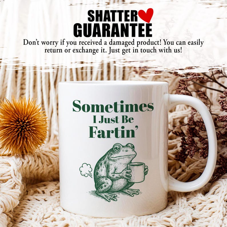 May include: White ceramic mug with the text "Sometimes I Just Be Fartin'" in green. A cartoon frog holding a cup is also featured. The mug has a white handle and is set against a neutral background.