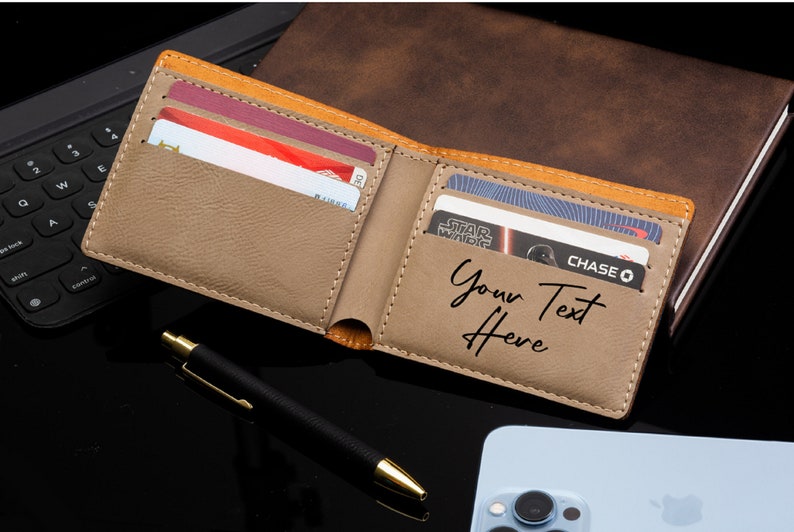 Puede incluir: Una cartera de cuero marr&oacute;n con ribete beige y una inscripci&oacute;n personalizada que dice "Your Text Here". La cartera est&aacute; abierta y tiene varias tarjetas de cr&eacute;dito en su interior.