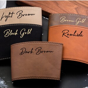 May include: Four different coloured leather cup holders with gold lettering. The colours are light brown, black, brown gold, and dark brown. The lettering says "Light Brown", "Black Gold", "Brown Gold", and "Dark Brown".