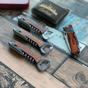 Pu&ograve; includere: Tre apribottiglie con manici in legno, ognuno con un cavatappi e un apribottiglie. Un coltellino tascabile con manico in legno e il nome "JORDAN" inciso su di esso.