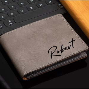 May include: A gray leather wallet with the name "Robert" embossed in black lettering.
