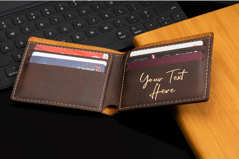 Puede incluir: Una cartera de cuero marr&oacute;n con un interior beige y una inscripci&oacute;n dorada que dice "Your Text Here". La cartera est&aacute; abierta y tiene varias tarjetas dentro.