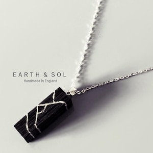 May include: A black rectangular pendant necklace with a silver chain. The pendant features a silver crackle design. The text "EARTH & SOL Handmade in England" is visible in the background.
