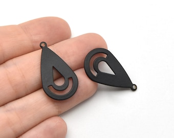 Puede incluir: Dos colgantes de pendientes negros mate en forma de lágrima. Cada colgante tiene un diseño recortado dentro de la forma de lágrima. Los colgantes tienen un pequeño agujero en la parte superior para sujetarlos a ganchos de pendientes. Fondo blanco.