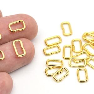 May include: Gold-colored rectangular metal jewelry findings. These open-ended, rectangular connectors are used in jewelry making. The findings are shown in a close-up view against a white background.