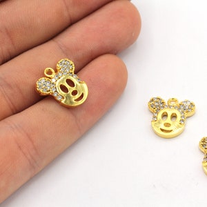 May include: Gold-colored Mickey Mouse charm pendants with clear crystal accents. The charms feature the iconic character's face and ears, with a loop for attaching to jewelry or other crafts. The charms are on a white background.