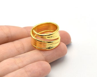 May include: A gold-colored ring with a textured, wrapped design. The ring has a unique, open style with two bands that wrap around the finger. The ring is shown on a white background.