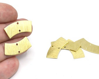 May include: Several gold-colored metal jewelry components. The components have a curved rectangular shape with a brushed texture and two small holes. Some components are in a hand, while others are scattered.