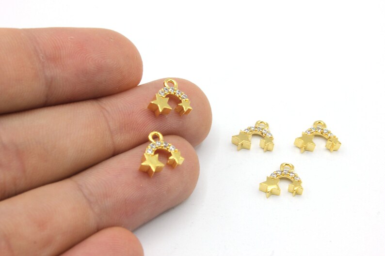 May include: Gold-coloured star charms with a curved bar of clear crystals. Each charm has two stars and a loop for attaching to jewellery. The charms are small and delicate, perfect for earrings or necklaces.