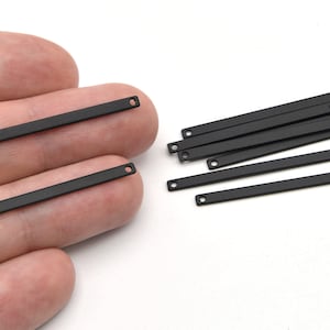 May include: A collection of matte black metal bar connectors with small holes at each end. These rectangular bars are shown in a variety of sizes and quantities, ideal for jewelry making or crafting projects. The bars are displayed against a white background.