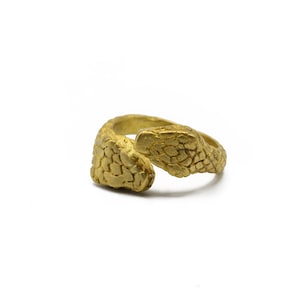May include: A gold-colored ring in the shape of a snake, with a textured surface. The snake's head and tail curve to meet, creating a unique and eye-catching design. The ring is set against a white background.