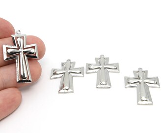 May include: Silver-colored cross pendants with a detailed design. The crosses have a loop at the top for hanging and are displayed against a white background. The image shows four crosses.