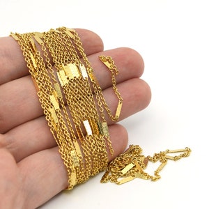May include: A gold-colored necklace with a delicate chain design. The necklace features rectangular bar accents throughout the chain. The jewelry is displayed against a white background.