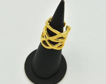 May include: A gold-colored ring with a woven design. The ring is displayed on a black jewelry stand against a white background. The ring's design features multiple interwoven bands, creating a textured appearance.