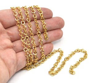 May include: A length of gold-colored chain with a series of small, round links. The chain is held in a hand against a white background. The chain is a jewelry component, suitable for necklaces or bracelets.