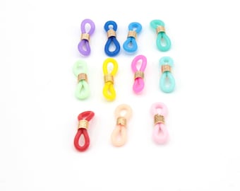 May include: A collection of colorful eyeglass holders in various shades, including purple, blue, green, yellow, pink, red, and peach. Each holder features a gold-colored metal connector.