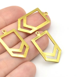 May include: Three gold-colored geometric pendants with a rectangular shape and a chevron design. Each pendant has a small loop at the top for attaching to a chain or other jewelry component. The pendants are shown against a white background.