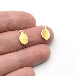 May include: Two small, gold-colored oval charms with a loop at the top for attaching to jewelry. The charms are smooth and shiny, with a simple, elegant design. Perfect for earrings or pendants.