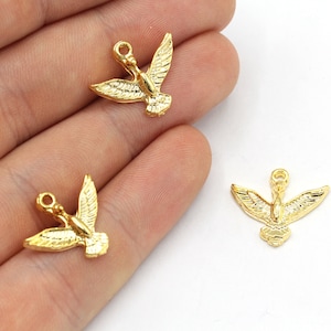 May include: Gold-colored bird charms with outstretched wings. These small, detailed pendants have a loop at the top for easy attachment to jewelry or other crafts. The charms are made of a shiny, metallic material.