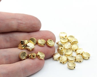 May include: Gold-colored seashell-shaped beads. These small, decorative beads have a detailed shell design and are ideal for jewelry making or craft projects. The beads are shown against a white background.