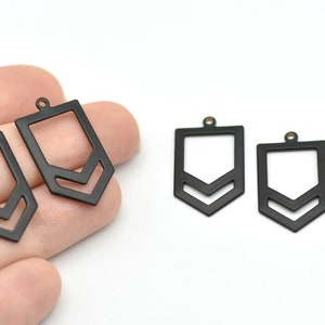 Könnte beinhalten: Schwarze Metall-Anhänger mit geometrischem Design und Chevron-Muster. Die Anhänger haben oben eine kleine Schlaufe zum Befestigen an Schmuck. Die Anhänger werden in verschiedenen Größen gezeigt.