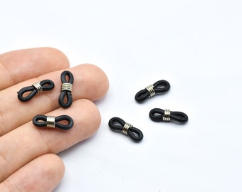 Puede incluir: Un conjunto de retenedores de gafas negros con bobinas de metal plateado. Los retenedores están hechos de un material flexible similar al caucho y están diseñados para sujetarse a las patillas de las gafas para mantenerlas seguras.