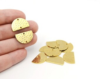 May include: Gold-coloured, half-circle metal jewellery findings with a hammered texture. Each piece has two small holes for attaching to other components. A hand holds two pieces, with several more scattered on a white surface.