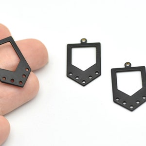 May include: Three black metal pendant charms with a geometric design. Each charm has a rectangular top with a small hole for hanging, and a downward-pointing arrow shape with six small holes at the bottom.