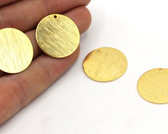 May include: Four gold-colored, round metal charms with a textured, brushed finish. Each charm has a small hole at the top for stringing. The charms are suitable for jewelry making or other craft projects.