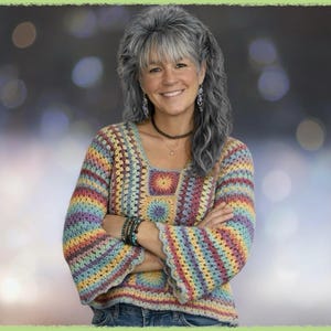 Könnte beinhalten: Ein mehrfarbiger Häkelpullover mit quadratischem Ausschnitt und Glockenärmeln. Der Pullover hat ein Regenbogenmuster mit Farben wie Gelb, Blau, Grün und Rosa. Die Frau trägt den Pullover mit einer blauen Jeans.