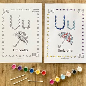 Pu&ograve; includere: Due fogli di attivit&agrave; bianchi con la lettera U, un'illustrazione di un ombrello e bordi a puntini. Un foglio &egrave; vuoto, l'altro &egrave; parzialmente colorato con punti blu e rossi. Sono inclusi due strisce di vaschette di vernice e tre cotton fioc.
