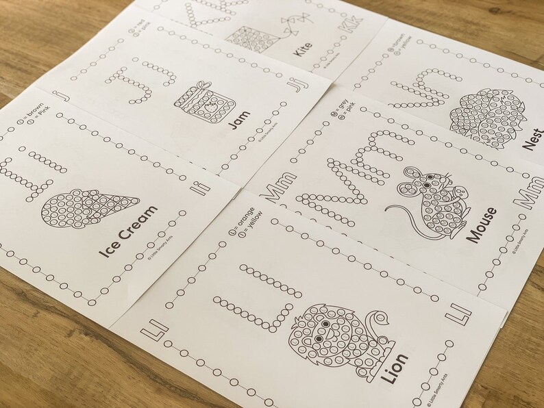 Pu&ograve; includere: Un set di fogli di attivit&agrave; educativi bianchi con disegni a linee nere di un aquilone, marmellata, nido, gelato, topo e leone. Ogni foglio include lettere dell'alfabeto formate da cerchi, chiavi di colore e etichette di testo corrispondenti.