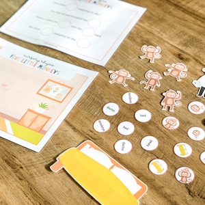 May include: A Five Little Monkeys nursery rhyme activity set featuring two printed activity sheets, a large bed cutout, five small monkey figures, a doctor figure, a parent figure, and several circular tokens with words and icons.