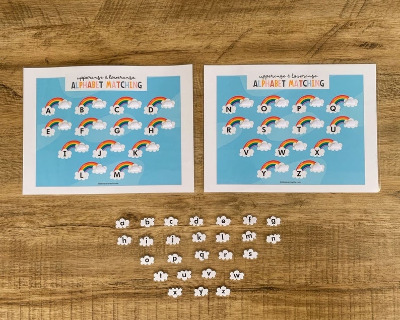 May include: Two white rectangular sheets featuring the text ALPHABET MATCHING and rainbow illustrations with uppercase letters A through Z. Below the sheets are individual white cloud-shaped cutouts, each printed with a lowercase letter from a to z.