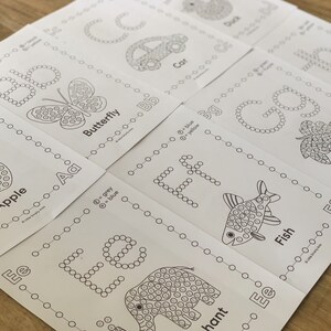 Pu&ograve; includere: Una raccolta di fogli di attivit&agrave; educativi bianchi con disegni a linee nere di lettere e oggetti come una mela, una farfalla, un'auto, un pesce, un elefante e uva. Ogni foglio include una guida a punti codificata per colore.