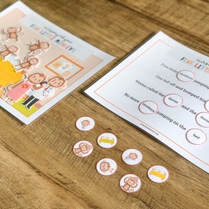 May include: An educational activity set featuring the nursery rhyme Five Little Monkeys, including a illustrated scene card, a text card with fill-in-the-blank circles, and several small circular tokens depicting monkeys, a doctor, and a bed.