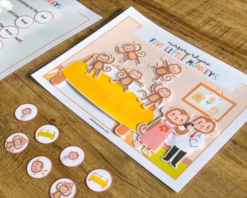 May include: A laminated educational activity sheet titled nursery rhyme FIVE LITTLE MONKEYS featuring a yellow bed, five brown monkey cutouts, and two adult monkey figures. Includes several small circular tokens with matching illustrations.