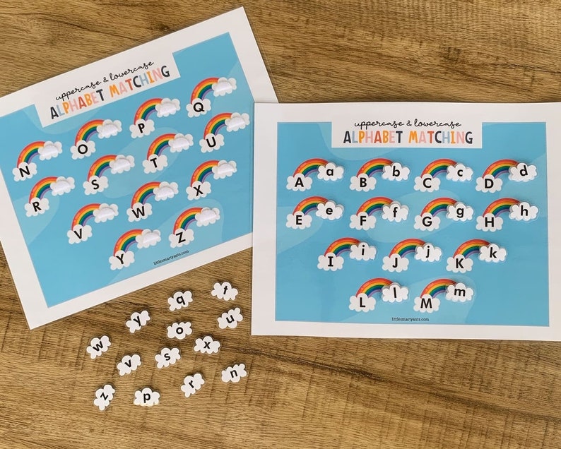 May include: Two white rectangular sheets with the text "uppercase & lowercase ALPHABET MATCHING" featuring rainbow and cloud illustrations with letters A through Z. A collection of small, individual white cloud-shaped pieces with lowercase letters.