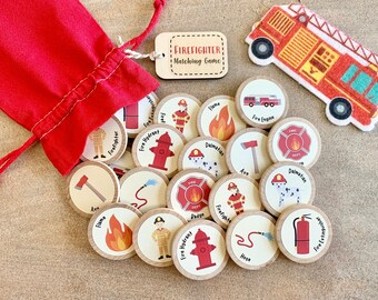 Peut inclure: Un sac rouge avec des pièces de jeu en bois illustrant des pompiers. Le jeu comprend des images d'un camion de pompiers, d'une borne-fontaine et d'un dalmatien. Une étiquette en bois indique "Firefighter Matching Game."