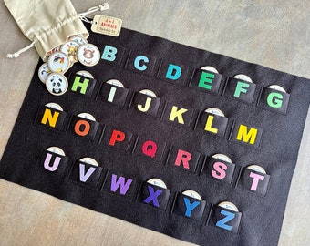 May include: A black felt alphabet board with colorful letters and matching animal picture discs. The board has pockets for each letter, and a drawstring bag holds additional discs. The tag reads "Animals Alphabet Set".