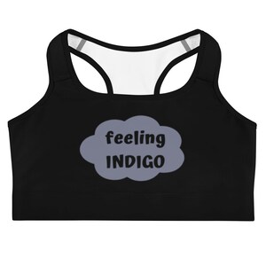 Puede incluir: Sujetador deportivo negro con forro blanco y una nube gris con el texto "feeling INDIGO" impreso en la parte delantera.