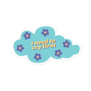 Peut inclure: Un nuage bleu avec des fleurs violettes et le texte "i need to cry first" en lettres jaunes.