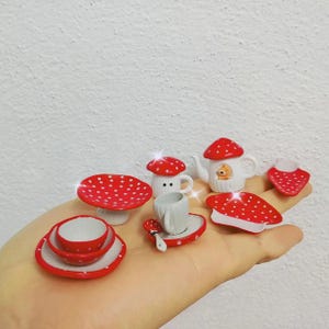 Può includere: Un set da tè in miniatura a tema fungo. Il set comprende una teiera, una tazza e un piattino, un piatto e un supporto per torte. Tutti i pezzi sono bianchi con pois rossi.