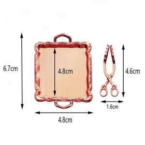 May include: A rose gold serving tray with ornate edges and a matching pair of tongs. The tray measures 4.8 inches by 6.7 inches.