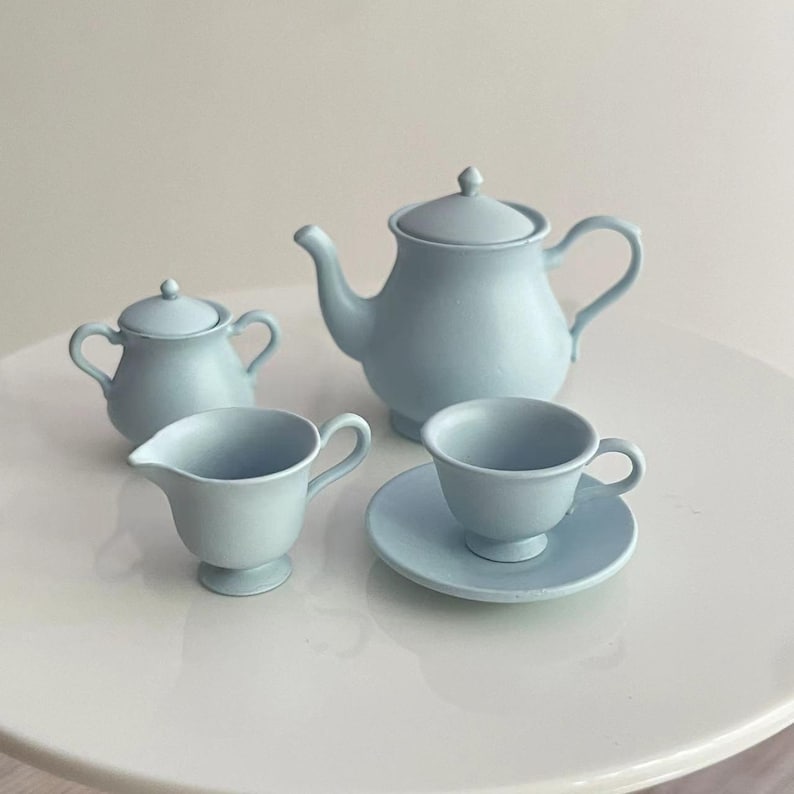 May include: A light blue tea set with a teapot, creamer, sugar bowl, and cup and saucer.