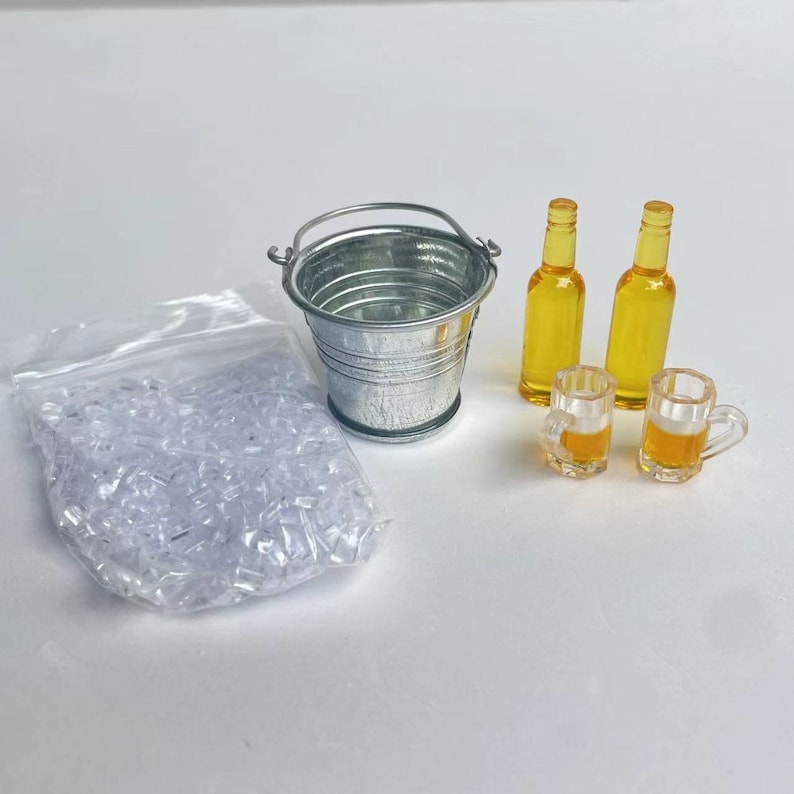 May include: A miniature metal bucket with a handle, two miniature glass bottles of beer, two miniature glass beer mugs, and a bag of clear plastic ice cubes.